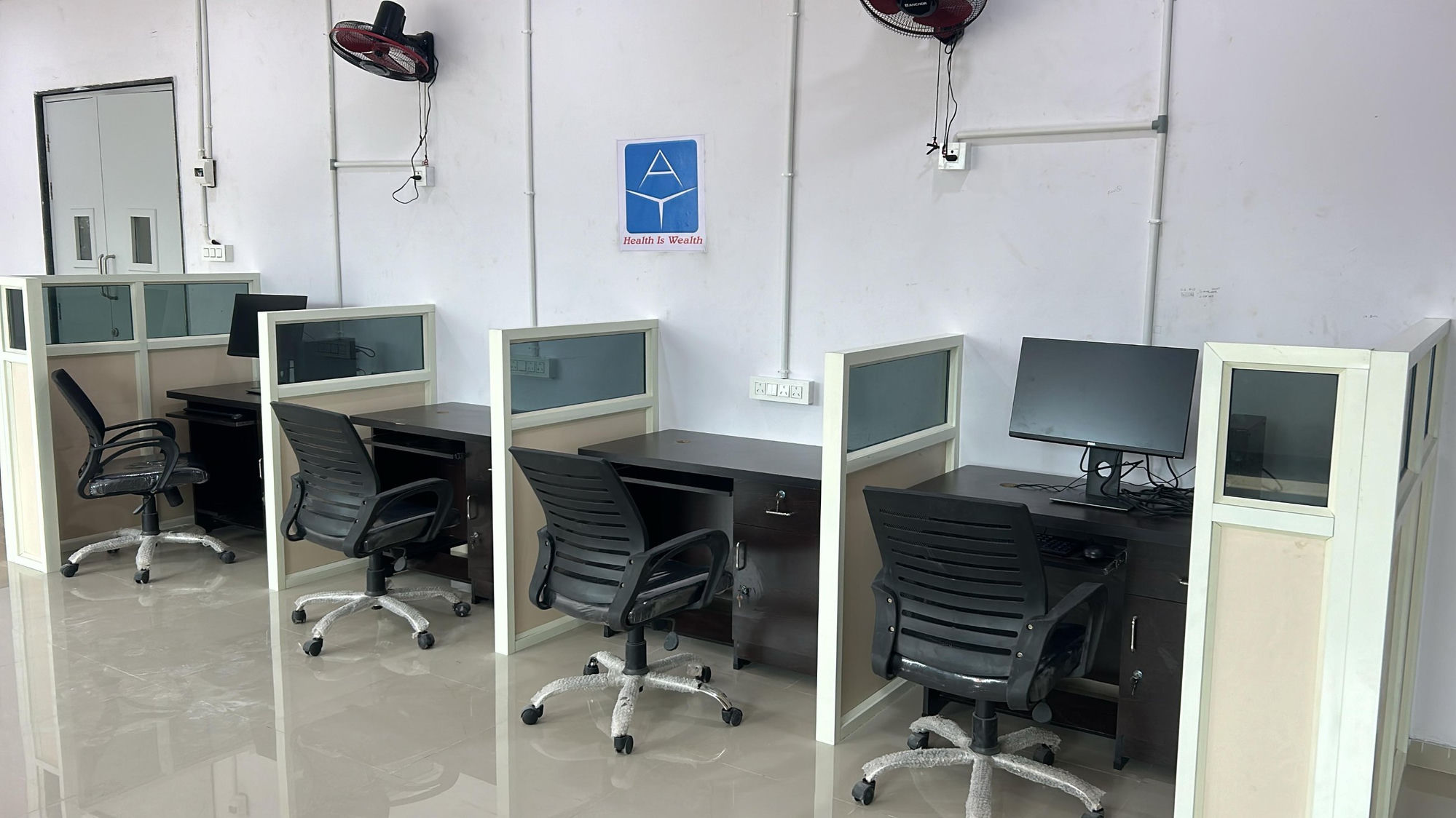 AIYOU Solutions open-plan workstations at AMTZ Visakhapatnam with the 'Health Is Wealth' wall logo